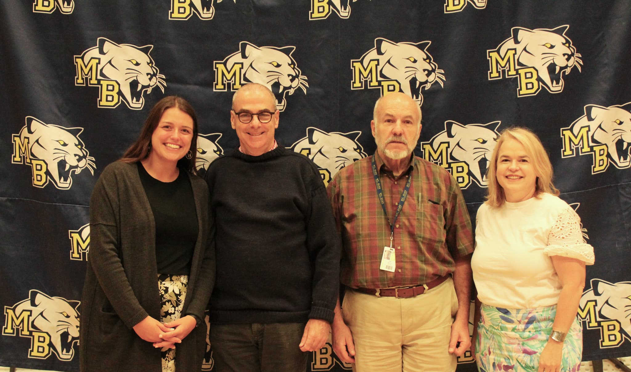 Four people pose in front of a Mt. Blue Background